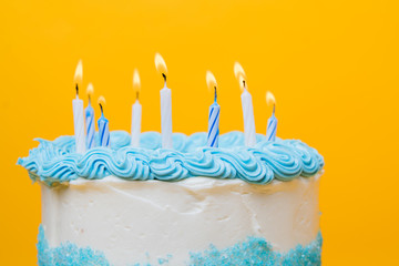 Frosted white cake with blue decorations and candles
