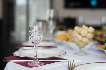 Glasses goblets on white table. Room with table serving fruits and dishes and meal.