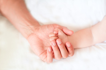 Obraz na płótnie Canvas Father holding the hand of his new born son