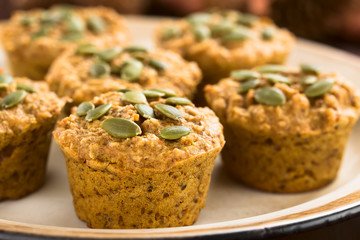 Fresh homemade pumpkin walnut oatmeal muffins with pepita pumpkin seeds on top (Selective Focus, Focus on the first two seeds on the first muffin)