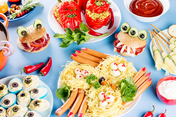 Halloween party food. Stuffed peppers with scary faces, cheese witches brooms, monster hamburgers, witch finger treats.