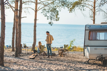 hippie couple having picnic with guitar at trailer near the sea