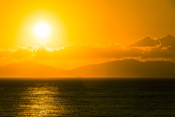 Sunrise over the sea and mountains on the horizon.