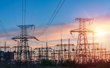 distribution electric substation with power lines and transformers, at sunset.