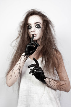 crazy girl with disheveled hair, black eyes and veins shows her finger shh. Halloween concept.