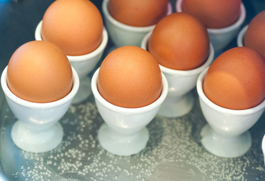 Egg cups with natural brown eggs in a boiler