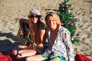 Happy Christmas holiday on the beach, cool young couple posing on sandy beach, singing and...