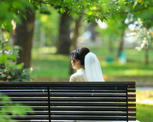 Fototapeta premium the bride sits alone on a bench in the park