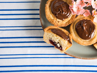 Cakes with frangipane, cherry jam and chocolate frosting. Romantic table setting with flowers. Mother's day card