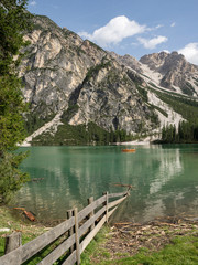 Fototapeta na wymiar Grüner See mit Holzzaun im Vordergrund und Bergen, Pragser Wildsee, Südtirol, Italien
