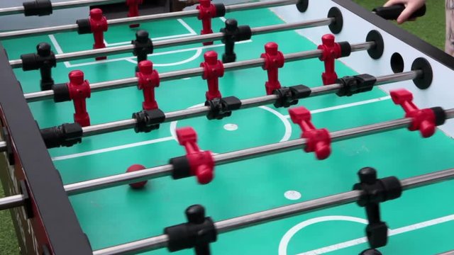 Playing foosball table game, close up view at green field with rotating player figures
