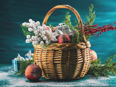 Christmas greeting card with basket full of holiday decorations. Festive new year background with gifts and snow on dark green