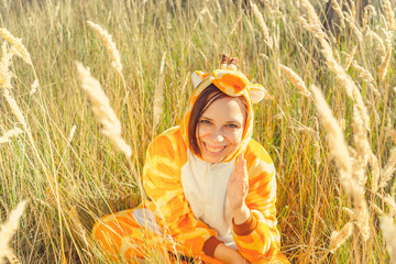 Girl smiles. Funny giraffe costume, Emotional student in funny pajamas sitting in a field of wheat....