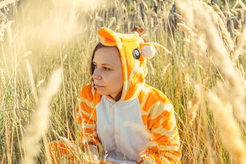 Funny giraffe costume, Emotional girl in funny pajamas sitting in a field of wheat. Concept...