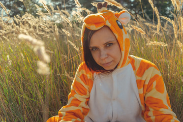 Funny giraffe costume, Emotional girl in funny pajamas sitting in a field of wheat. Concept...