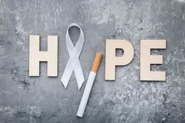 White ribbon with cigarette and inscription Hope. Cancer concept