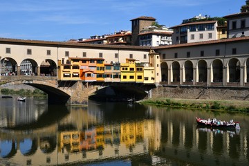 Fototapeta na wymiar Tourists on the boat under the Ponte Vecchio in Florence reflecting on the waters of the river Arno. Italy.