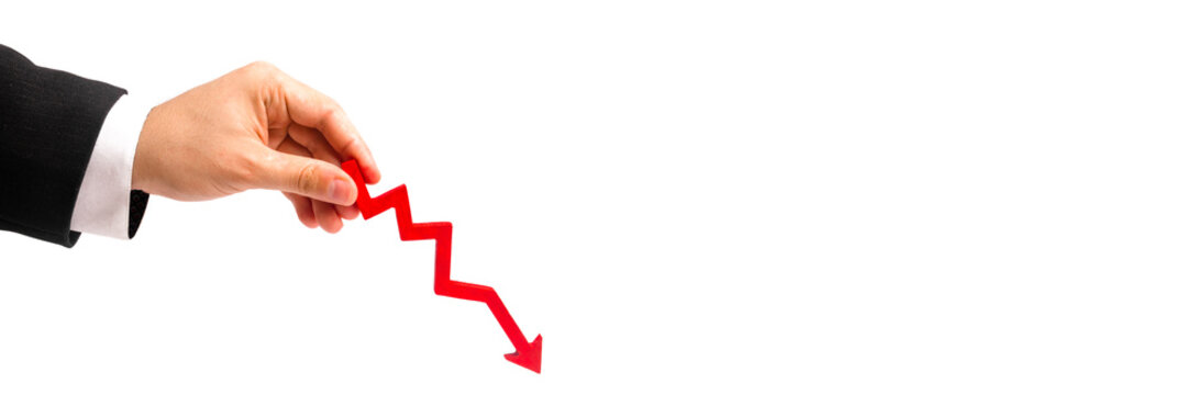 A businessman's hand is holding a red arrow down on a white background. concept of reducing costs and profits