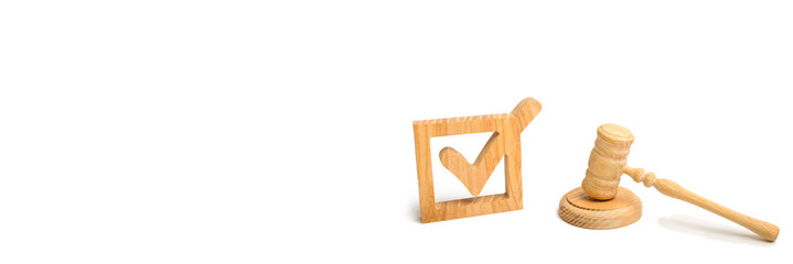A wooden checkmark and a hammer of the judge on a white background. referendum and elections....