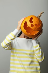 Female hands holding halloween pumpkin on grey background