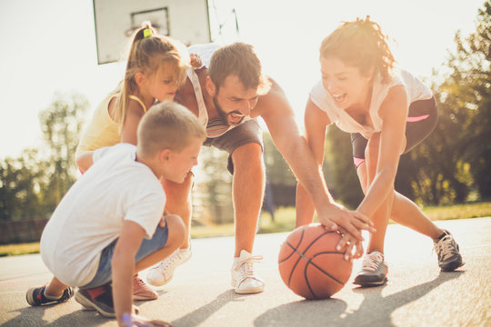 Family outside playing basketball together.