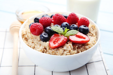 Oatmeal with berries in bowl on wooden table
