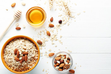 Oatmeal in bowl with nuts on white wooden table