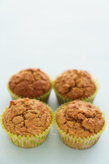 Four carrot muffins on a light blue background. Space on top, high resolution