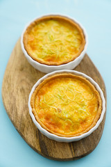 Gluten free leek mini quiches on a wooden board served with fresh rukkola, tomatoes and cheese