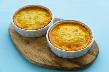 Gluten free leek mini quiches on a wooden board served with fresh rukkola, tomatoes and cheese