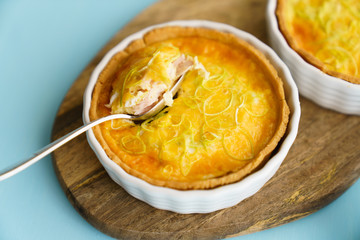 Gluten free leek mini quiches on a wooden board served with fresh rukkola, tomatoes and cheese
