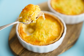 Gluten free leek mini quiches on a wooden board served with fresh rukkola, tomatoes and cheese