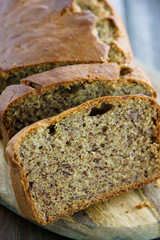 Banana bread on a wooden board served with fresh bananas