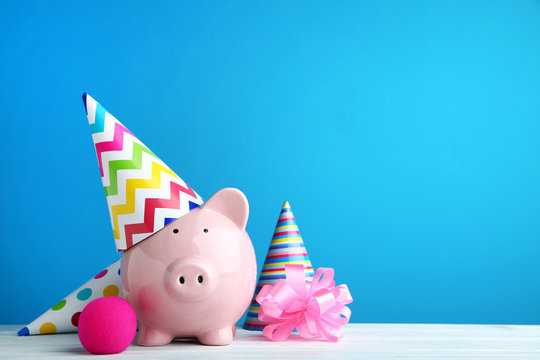 Pink piggy bank with birthday cap on blue background