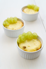 Mini zapekankas (baked quark dessert) with raisins and fresh grape. White wooden table, high resolution
