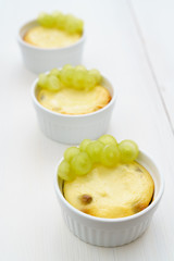 Mini zapekankas (baked quark dessert) with raisins and fresh grape. White wooden table, high resolution