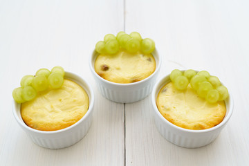 Mini zapekankas (baked quark dessert) with raisins and fresh grape. White wooden table, high resolution