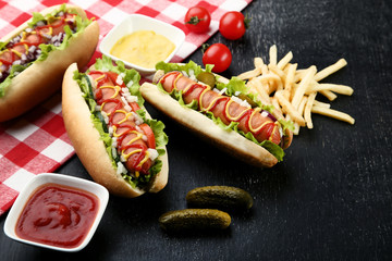 Hot dogs with vegetables and french fries on wooden table