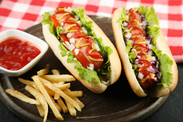 Hot dogs with vegetables and french fries on wooden table