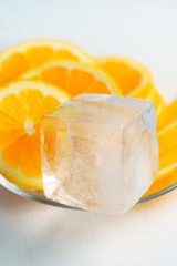 Ice cube with orange slices on a glass plate. Macro shot, high resolution
