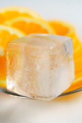 Ice cube with orange slices on a glass plate. Macro shot, high resolution