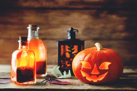 Glowing pumpkin with jars on dark wood background. Halloween concept.