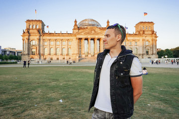 smiling tourist stands at the reihstag in berlin on the sunset