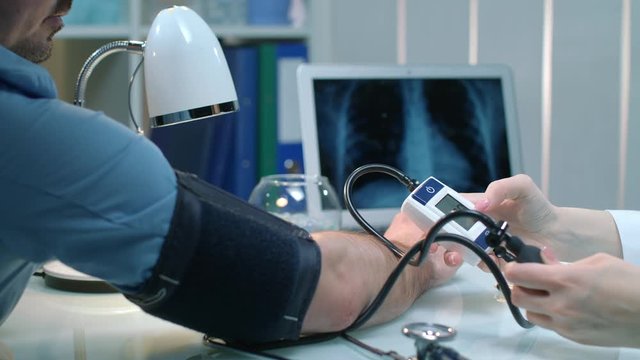 Nurse taking blood pressure for man. Close up of doctor care patient. Male patient check blood pressure at doctor workplace. Female doctor check arterial pressure of cardiology patient