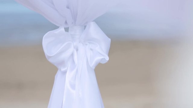 Wedding decorations of white fabrics and flowers on the beach before the ceremony