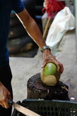 Homme coupant une noix de coco
