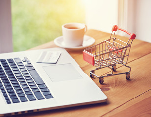 laptop with credit card and trolley as symbol of online shopping and paying