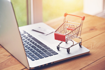 laptop with credit card and trolley as symbol of online shopping and paying