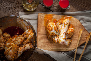 Marinated chicken drumsticks on a wooden chopping board.