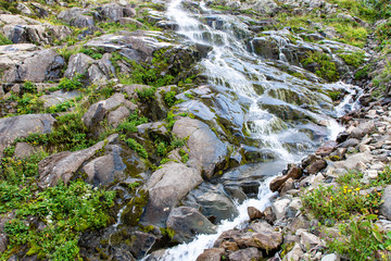 Beautiful cascade mountain waterfall in the green mountainside.